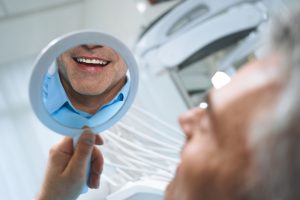 Man sees smile in hand-held mirror.